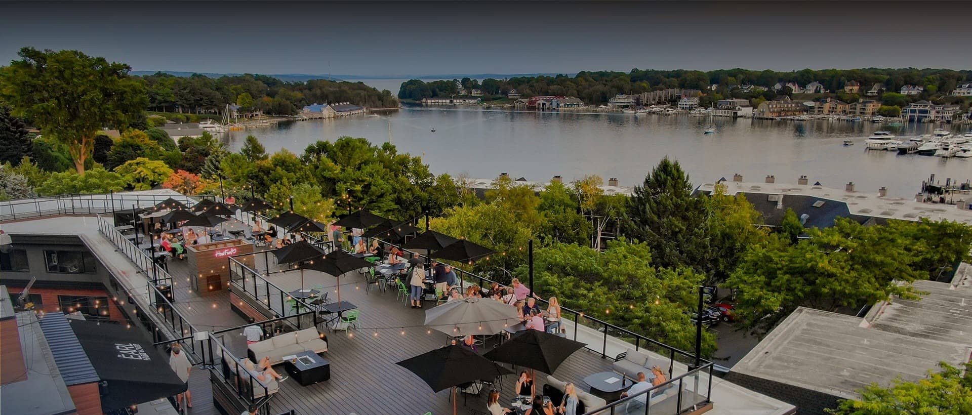 A group of people sitting at a table on a rooftop overlooking a lake