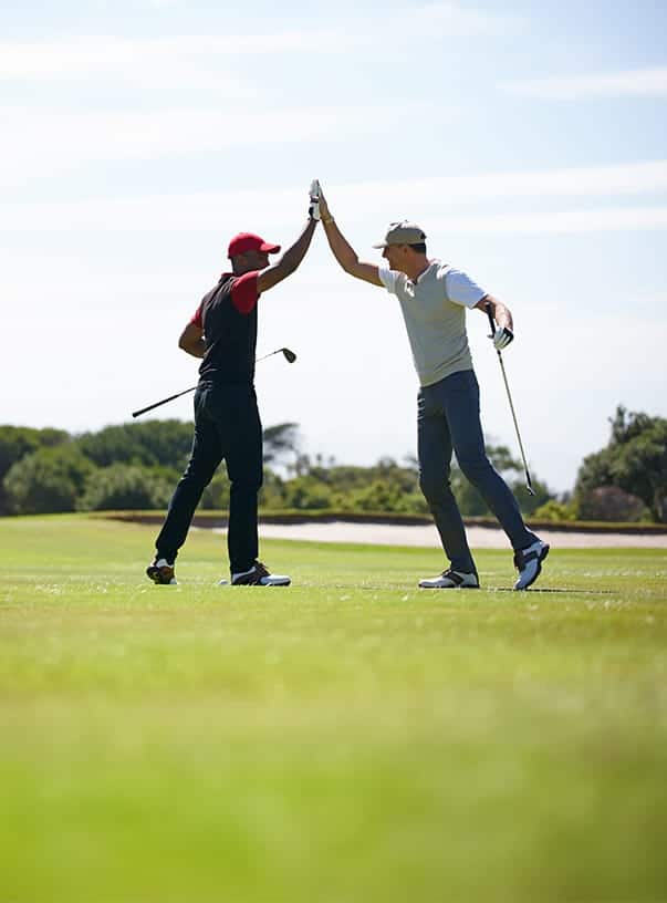 Two men on a golf course high fiving