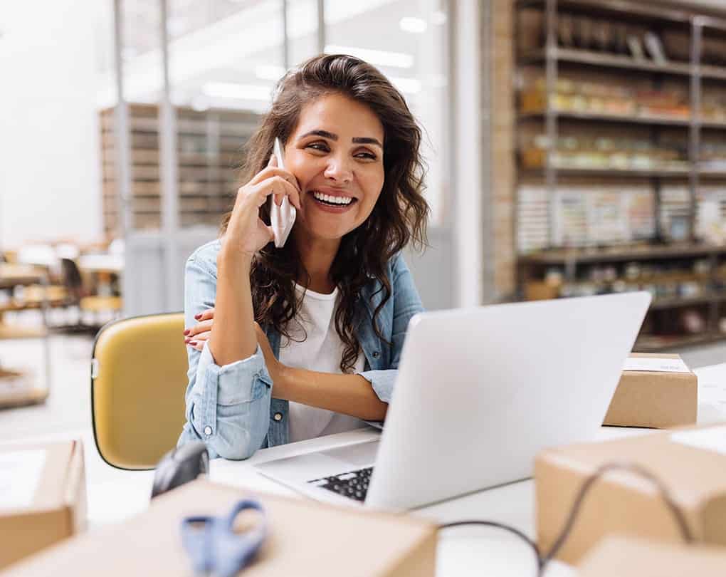 A woman sitting at a desk talking on a cell phone
