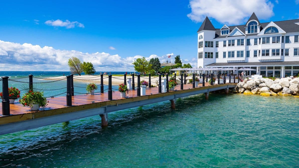 A dock over blue water leading to a large white hotel
