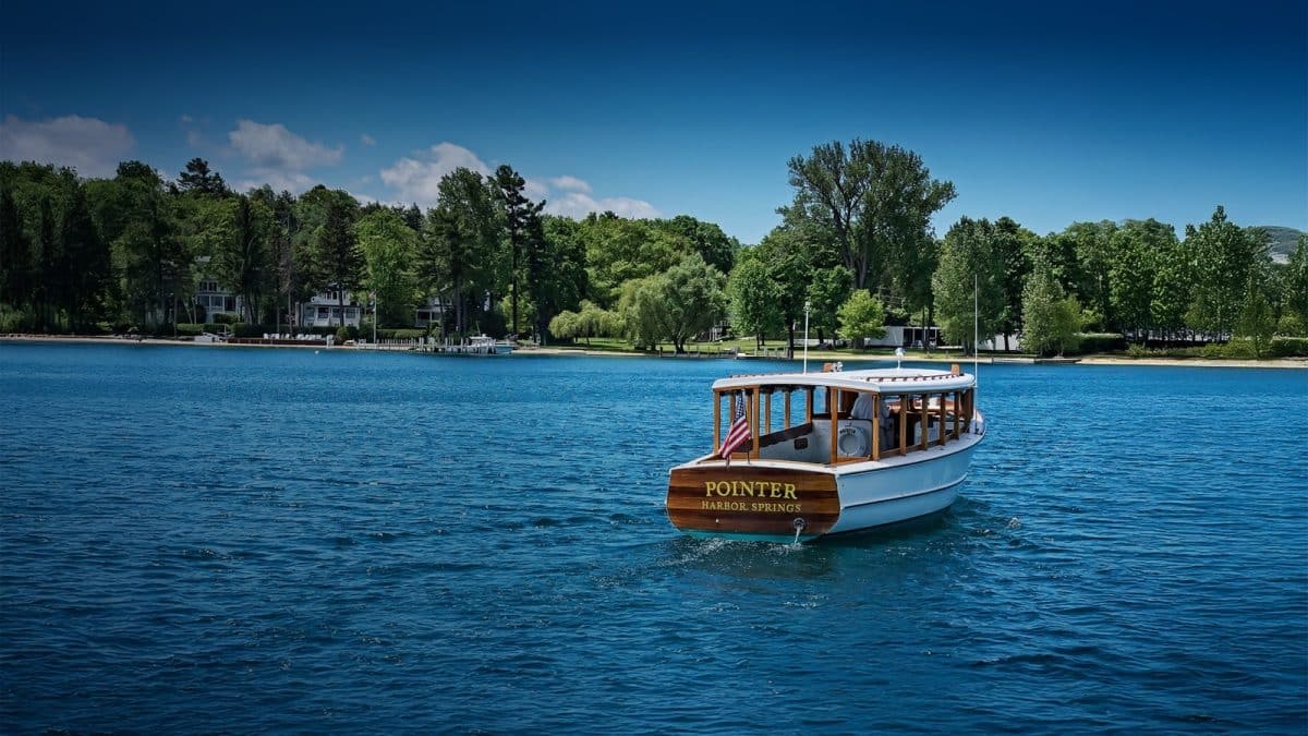 A wooden boat named Pointer cruising on a blue bay