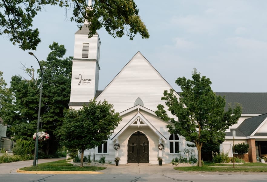 A white church with a steeple and trees
